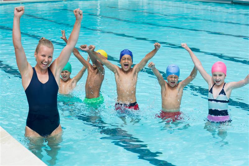 A swim instructor and five children in swim caps stand in a pool, raising their arms and cheering with excitement—much like a successful franchise onboarding, everyone is splashing water, happy and enthusiastic. A swim instructor and five children in swim caps stand in a pool, raising their arms and cheering with excitement—much like a successful franchise onboarding, everyone is splashing water, happy and enthusiastic.